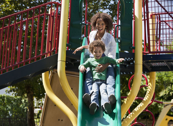 Mother and son sliding down slide