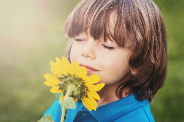 Child smelling a yellow flower