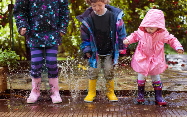 Three kids splashing in a water puddle