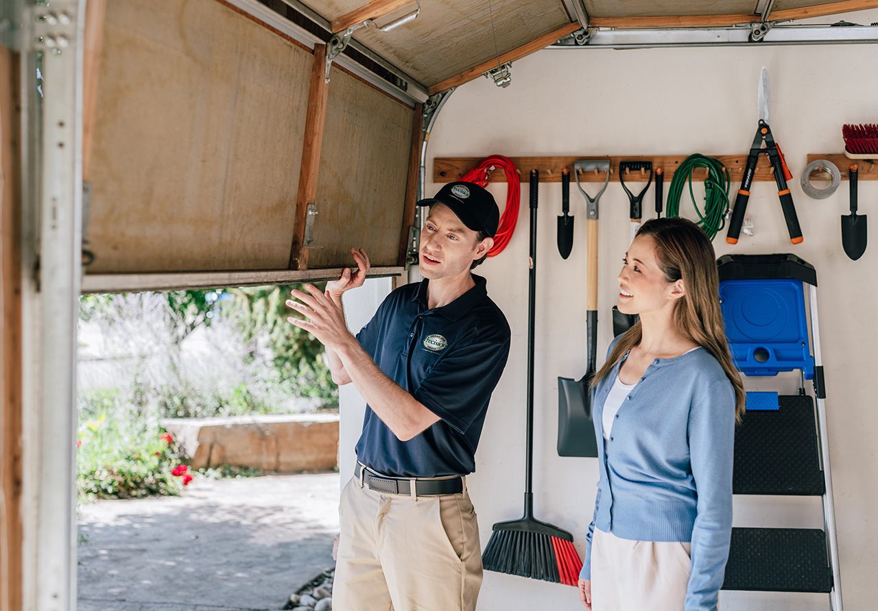 Representative from Precision garage door inside the garage with the homeowner inspecting the bottom of the door.