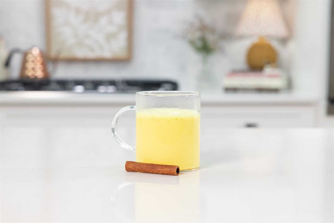A glass of golden milk, warm Organic Valley<sup><sup><sup><sup><sup><sup><sup><sup><sup>&reg;</sup></sup></sup></sup></sup></sup></sup></sup></sup> Whole Milk spiced with turmeric, cinnamon and a touch of maple syrup, on a counter in the kitchen.