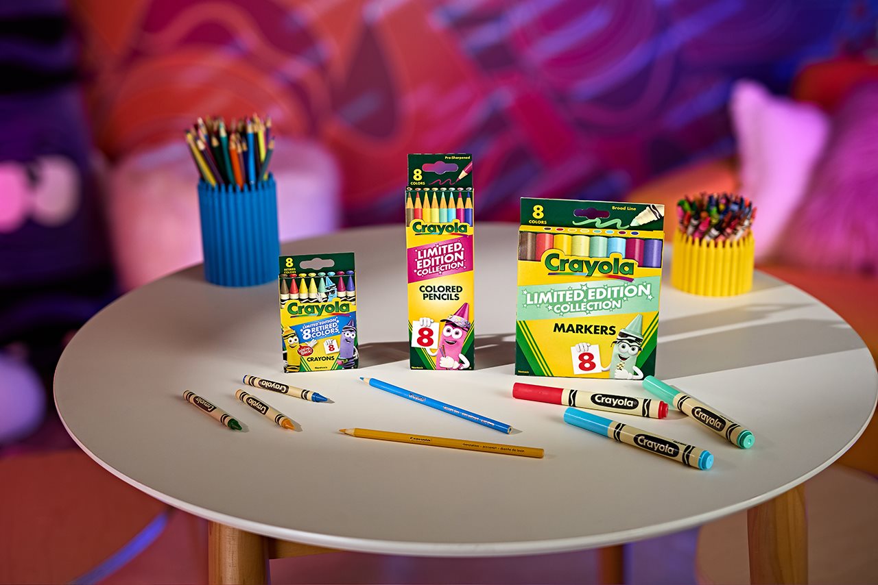 Limited Edition Crayola family of product on a small table if front o a colorful background.