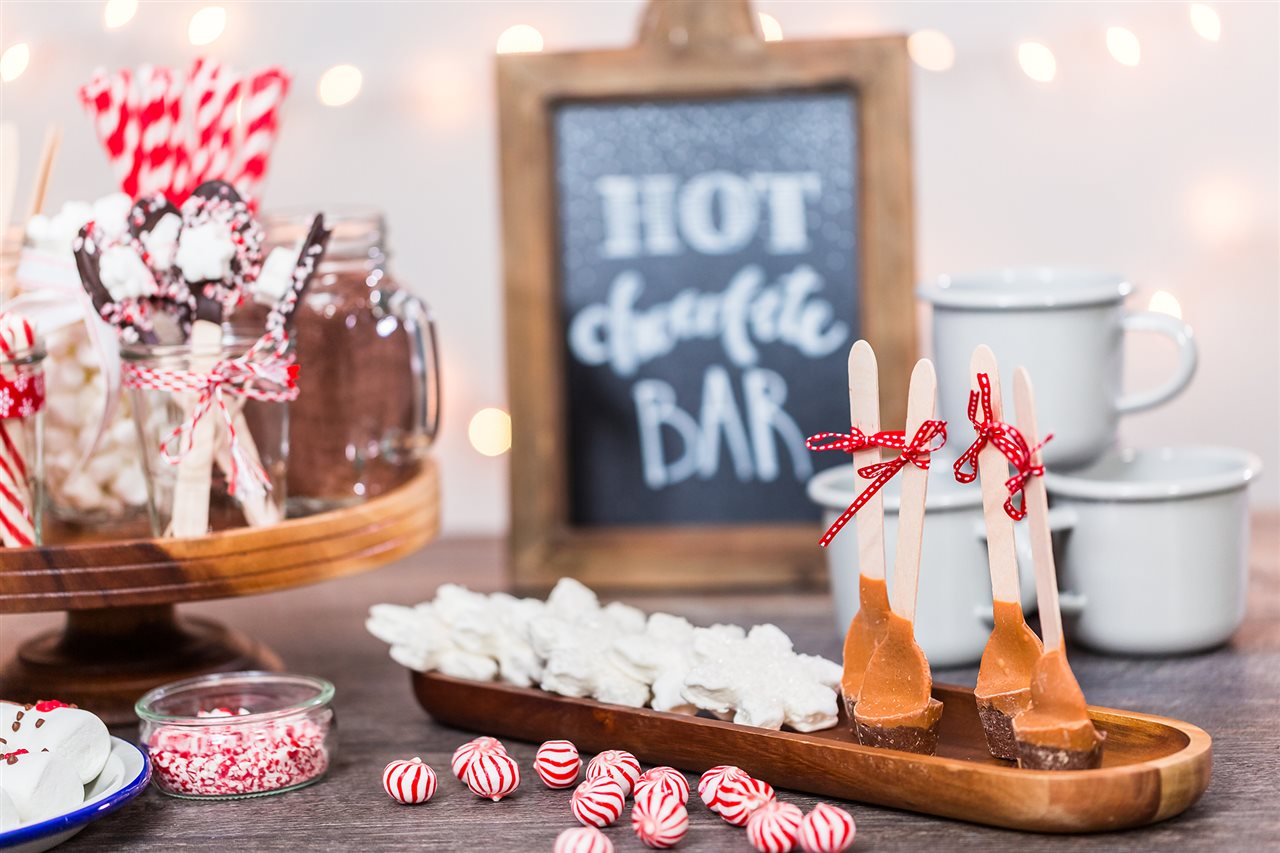 A hot chocolate bar with cups, peppermints, carmel chocolate drizzles and other sweets.