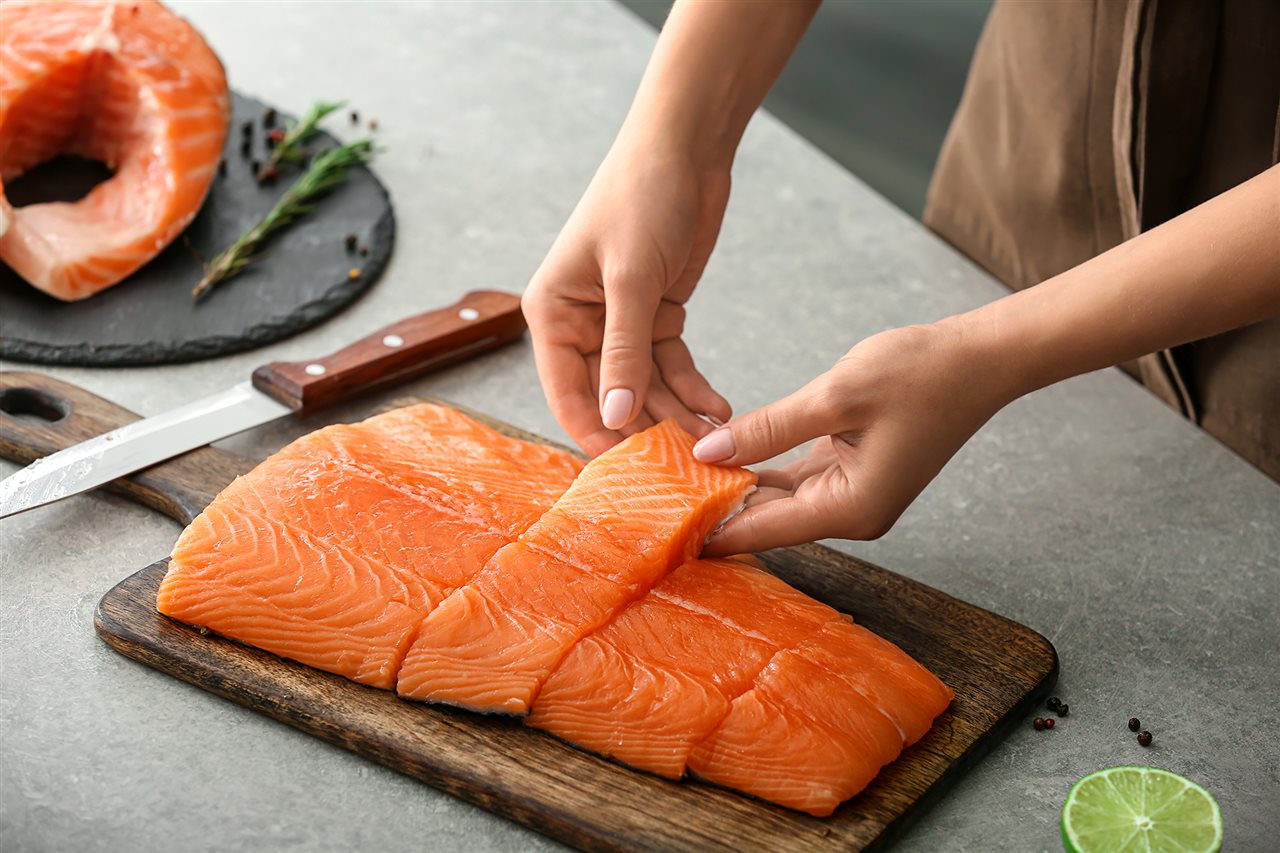 Woman cutting salmon into serving portions.