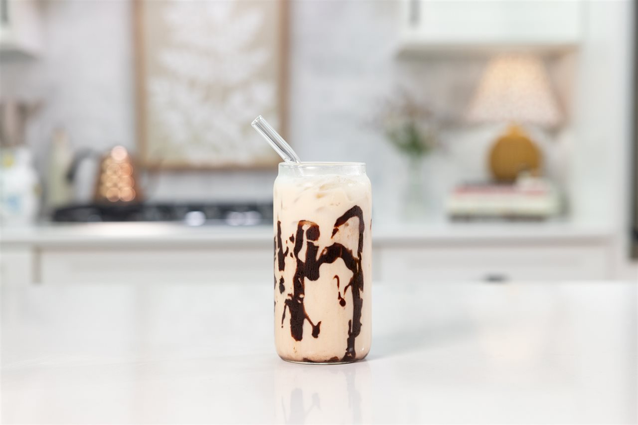 A glass of peanut butter banana mocha, chocolate, espresso, banana and peanut butter milk, on a counter in the kitchen.