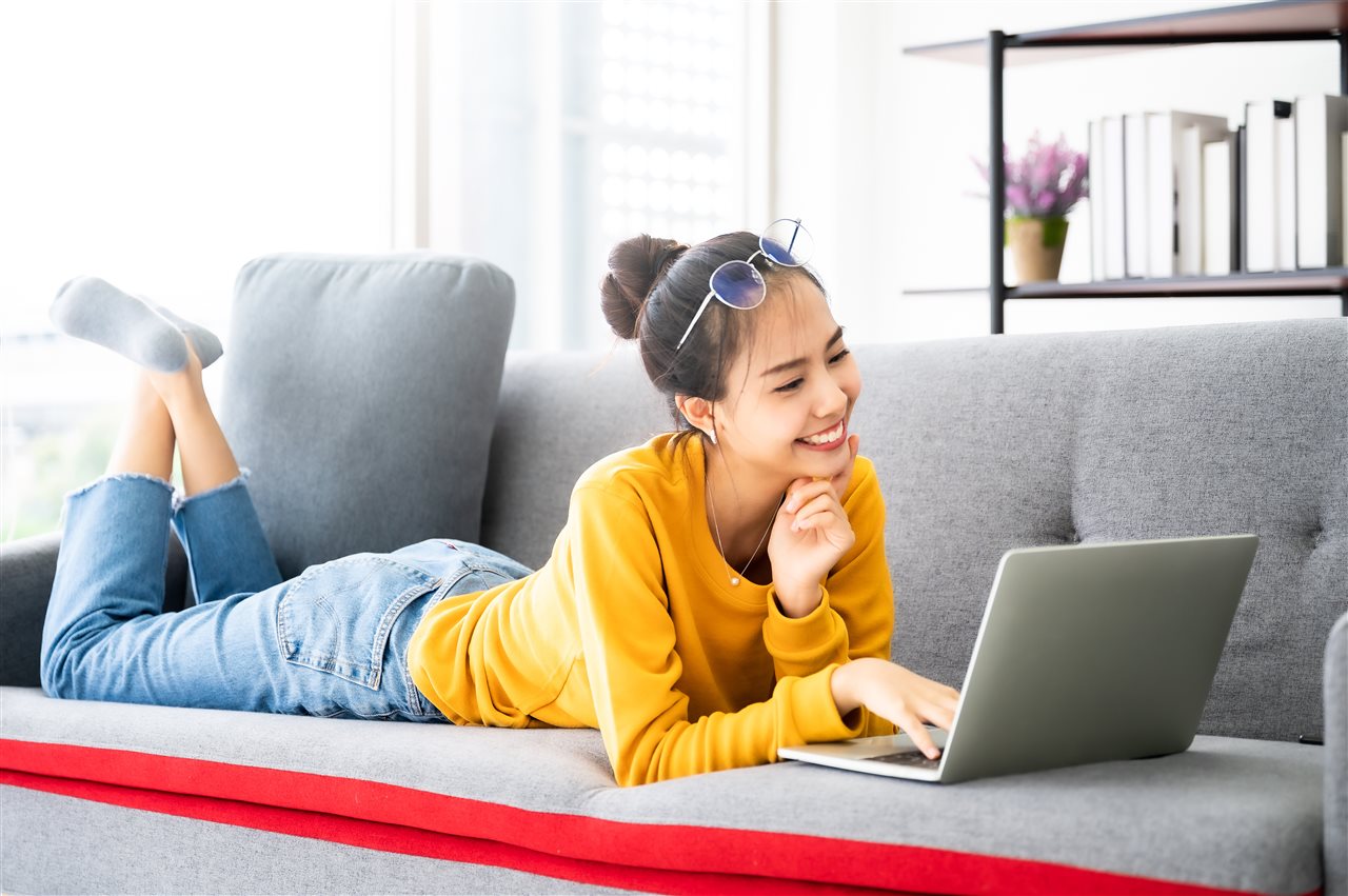 Teenager girl on couch with laptop about Pearson's Connections Academy AI policy for responsible AI use to help her become confident, adaptable, lifelong learner.