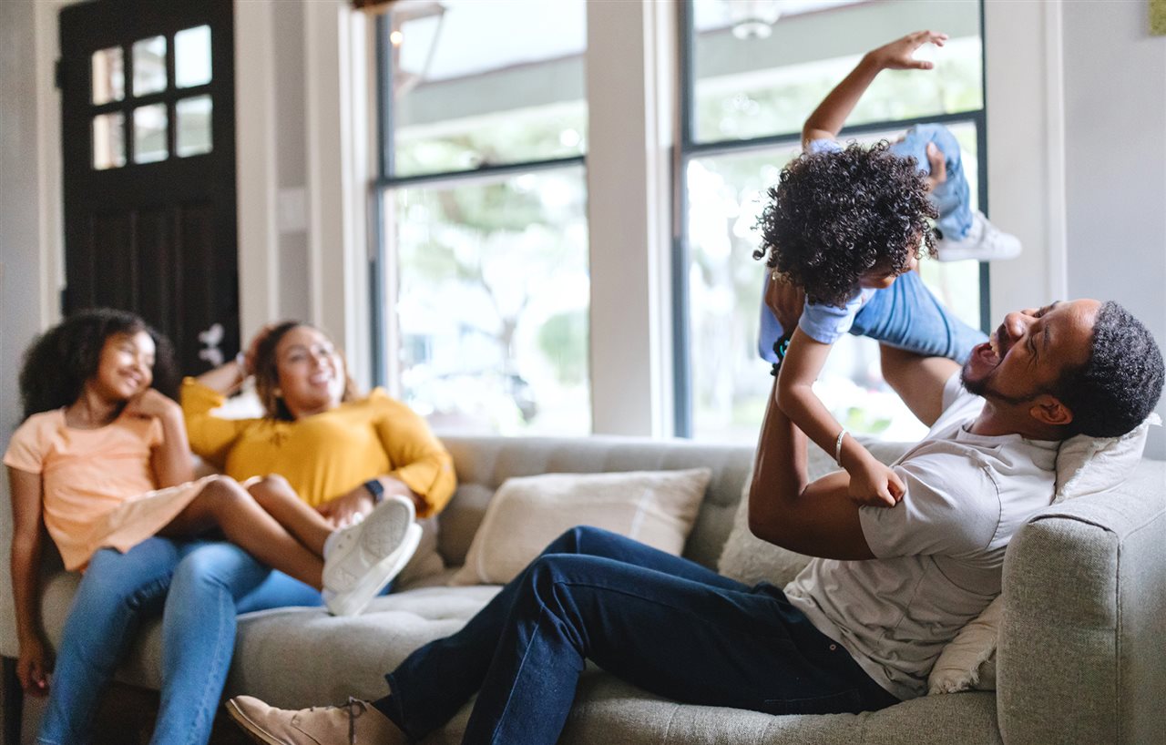 Couple and kids playing on the couch in their livingroom.