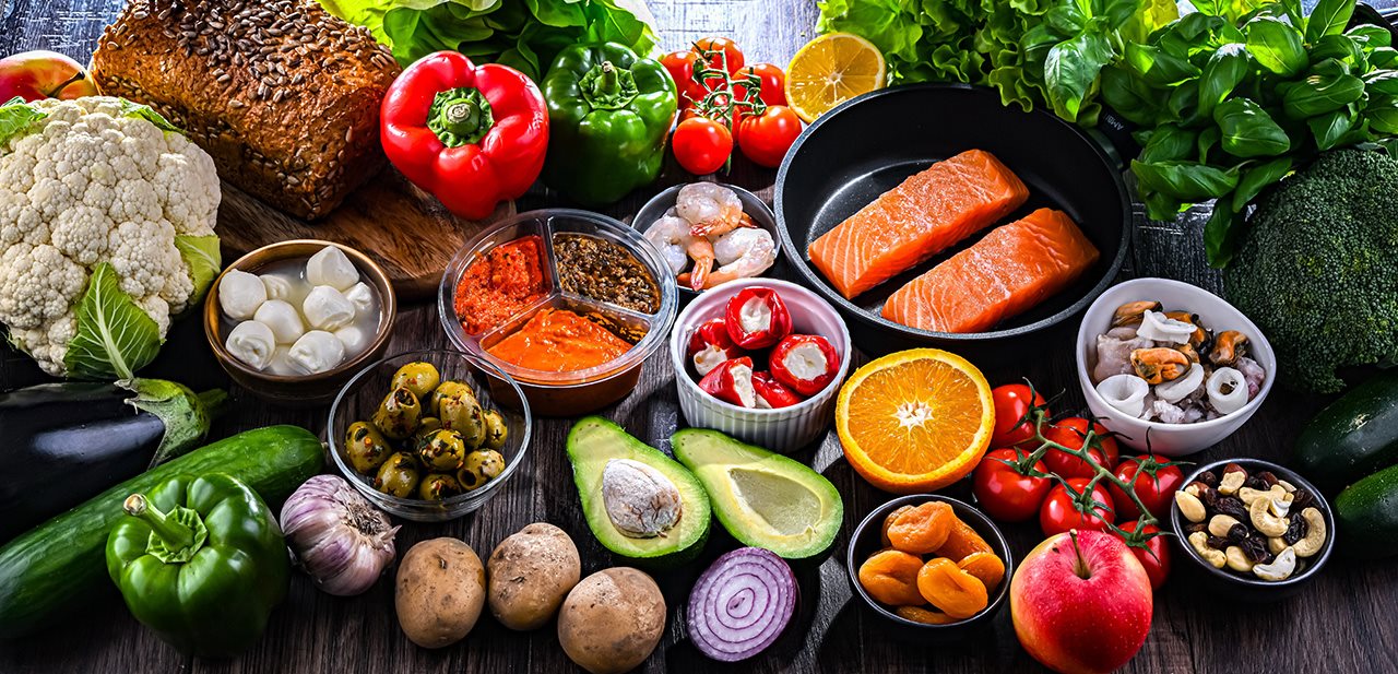 A table with various proteins, vegetables and fruits laid out.