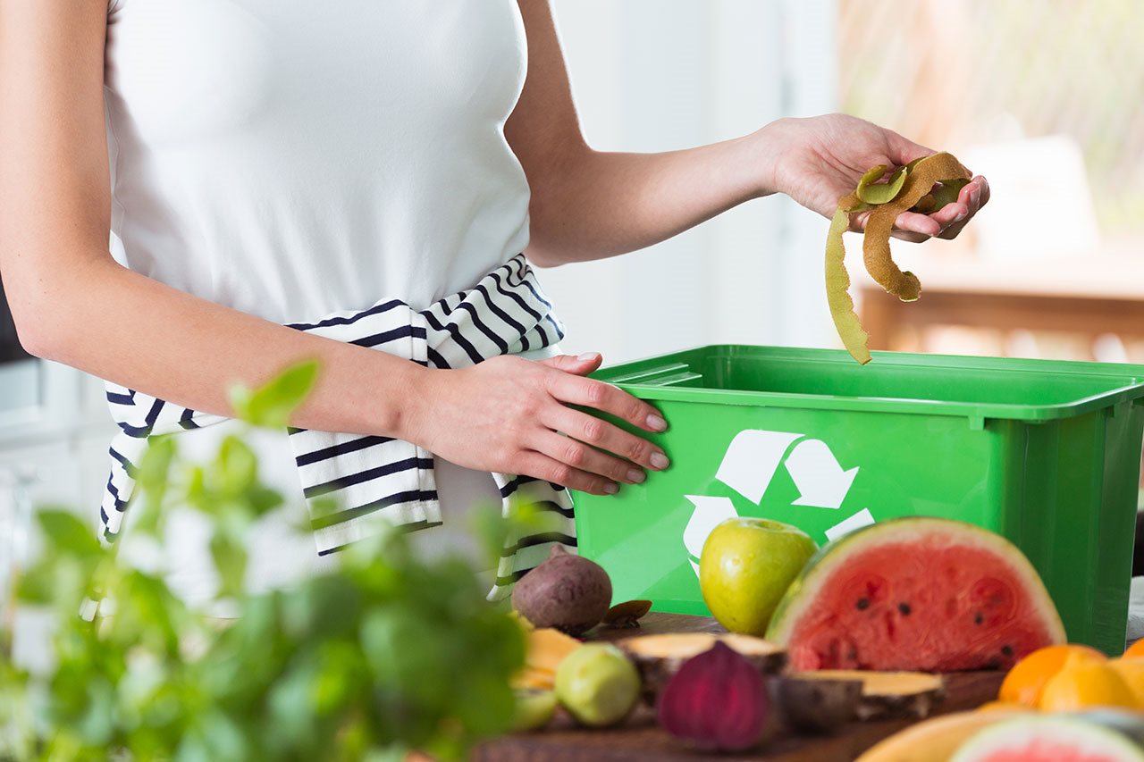 Woman composting peelings in a recyclible container.