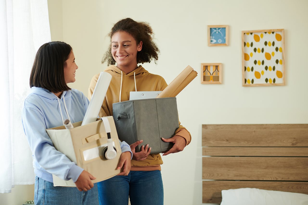 Two young women carrying shopping bags to their dorm room.