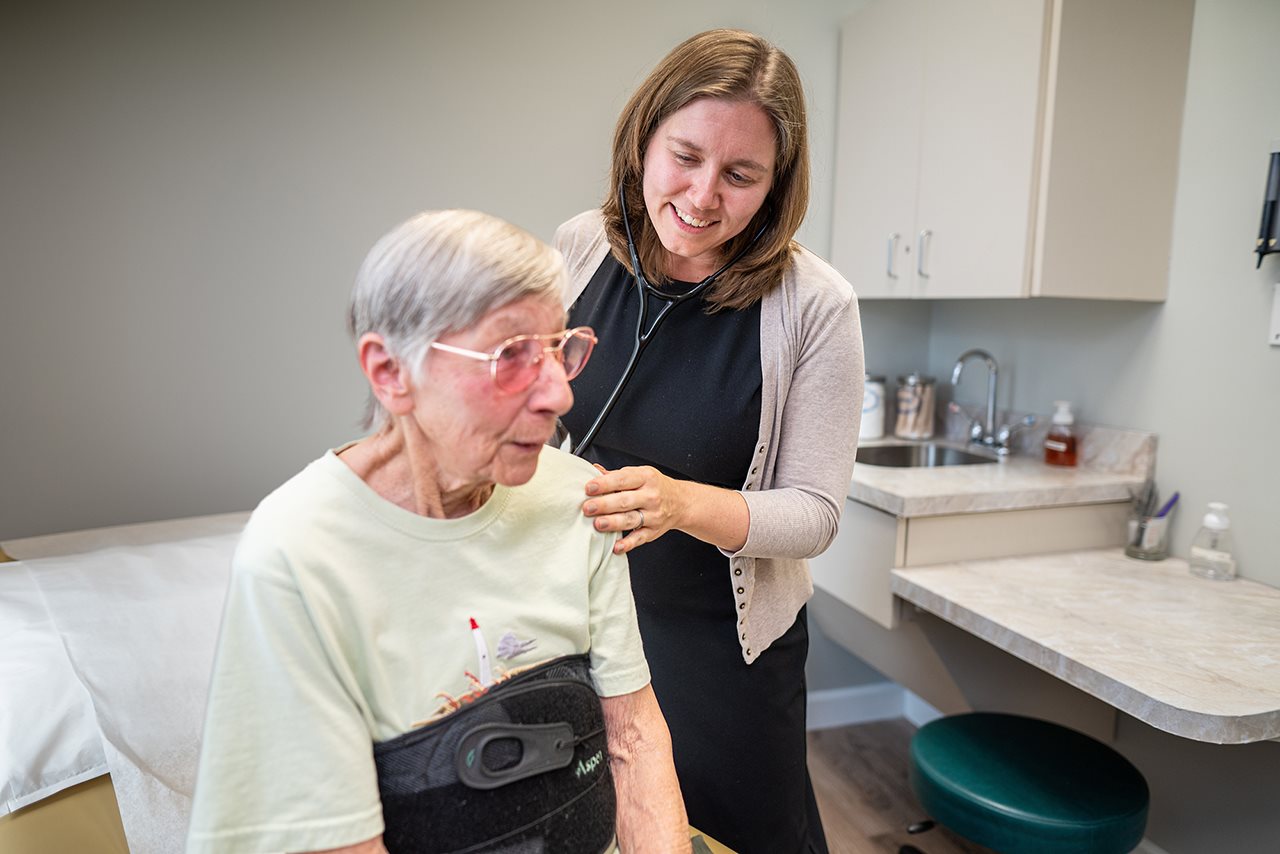 Doctor examining older woman in exam room.