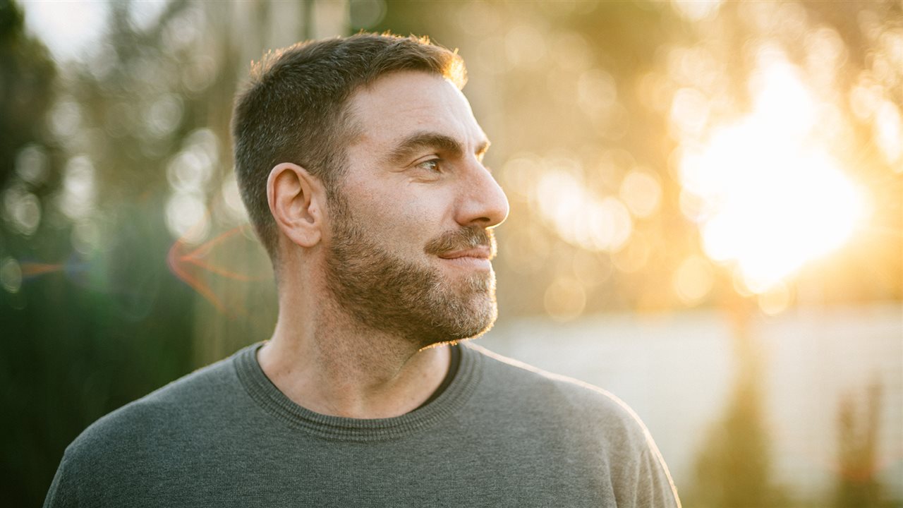 Smiling man wearing a t-shirt outside.