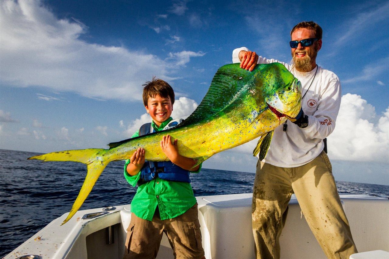 Father and son on a boat in Corpus Christi pulling in a big fish.