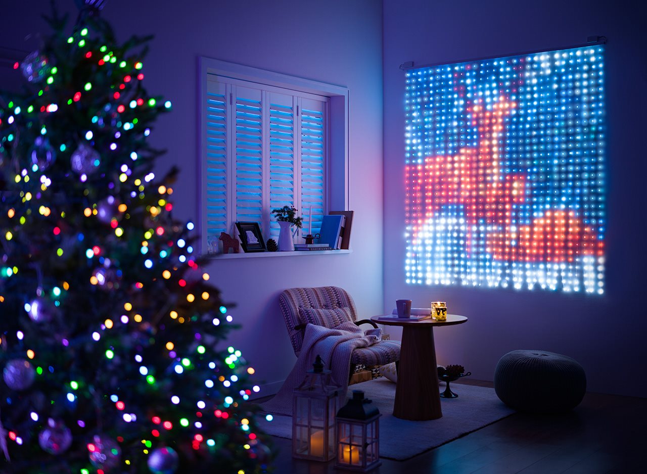 A Christmas tree by a light display on the wall showing reindeer.