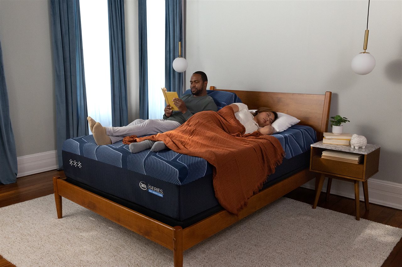A man reading and a woman sleeping on a Serta's new iSeries NXG&trade; mattress.