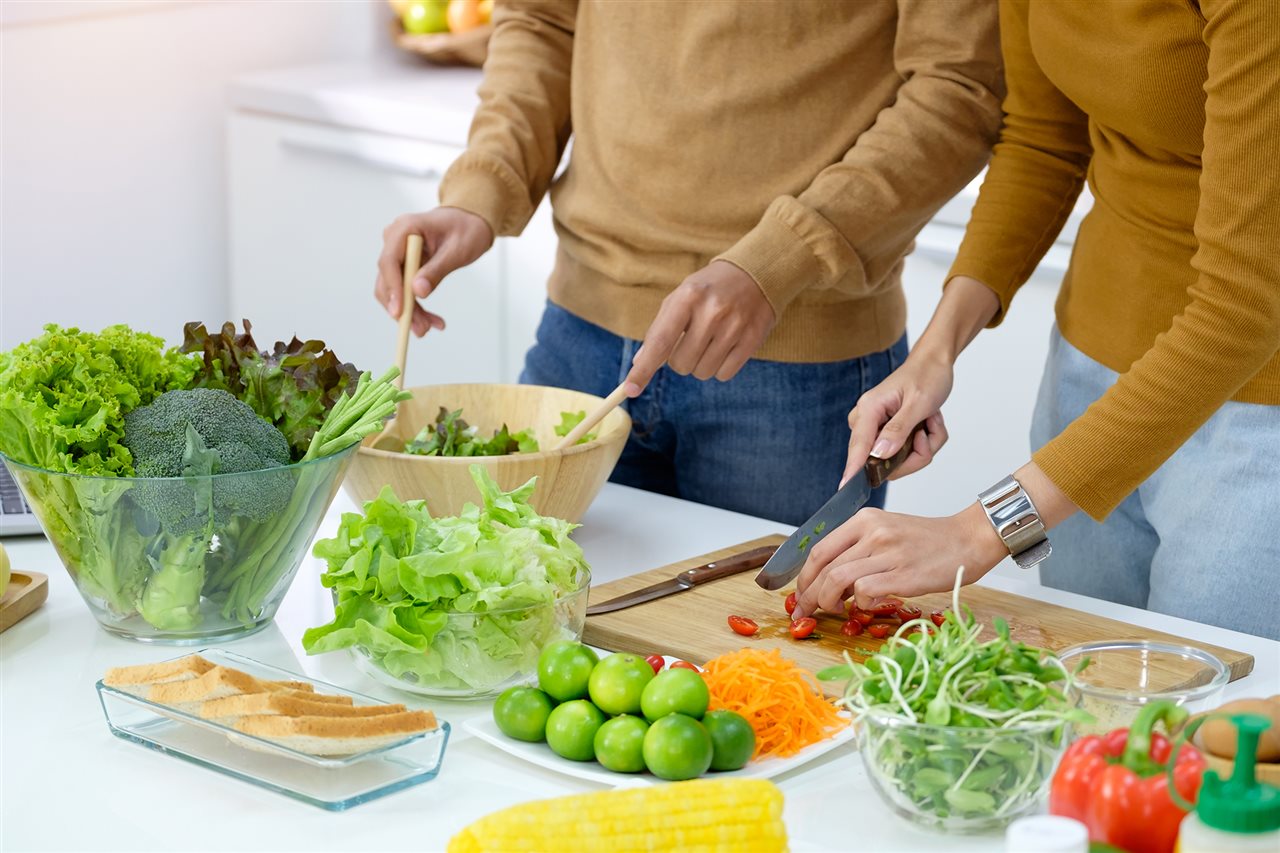 Couple preparing green vegetables for a salad.