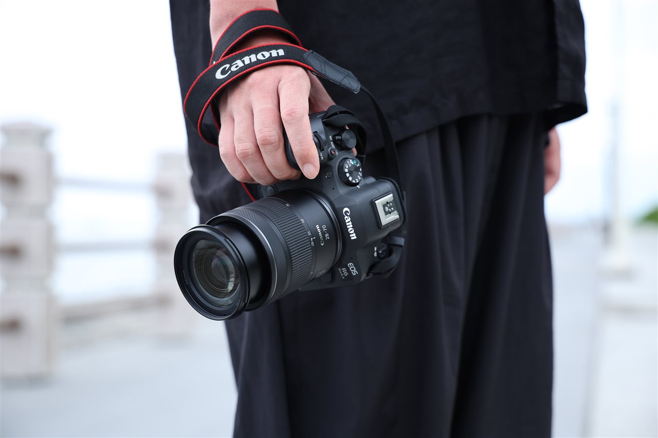 Man holding at his side a Canon RF28-70