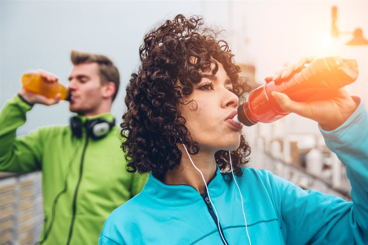 Woman and man drinking from water bottles