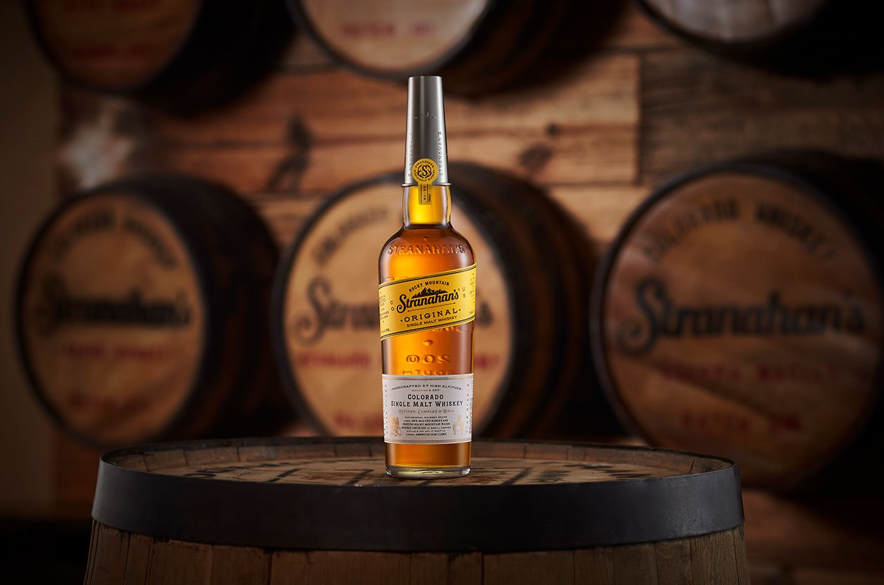 A bottle of Strananhan Original whiskey sitting on a whiskey barral with whisky barrals in the background.
