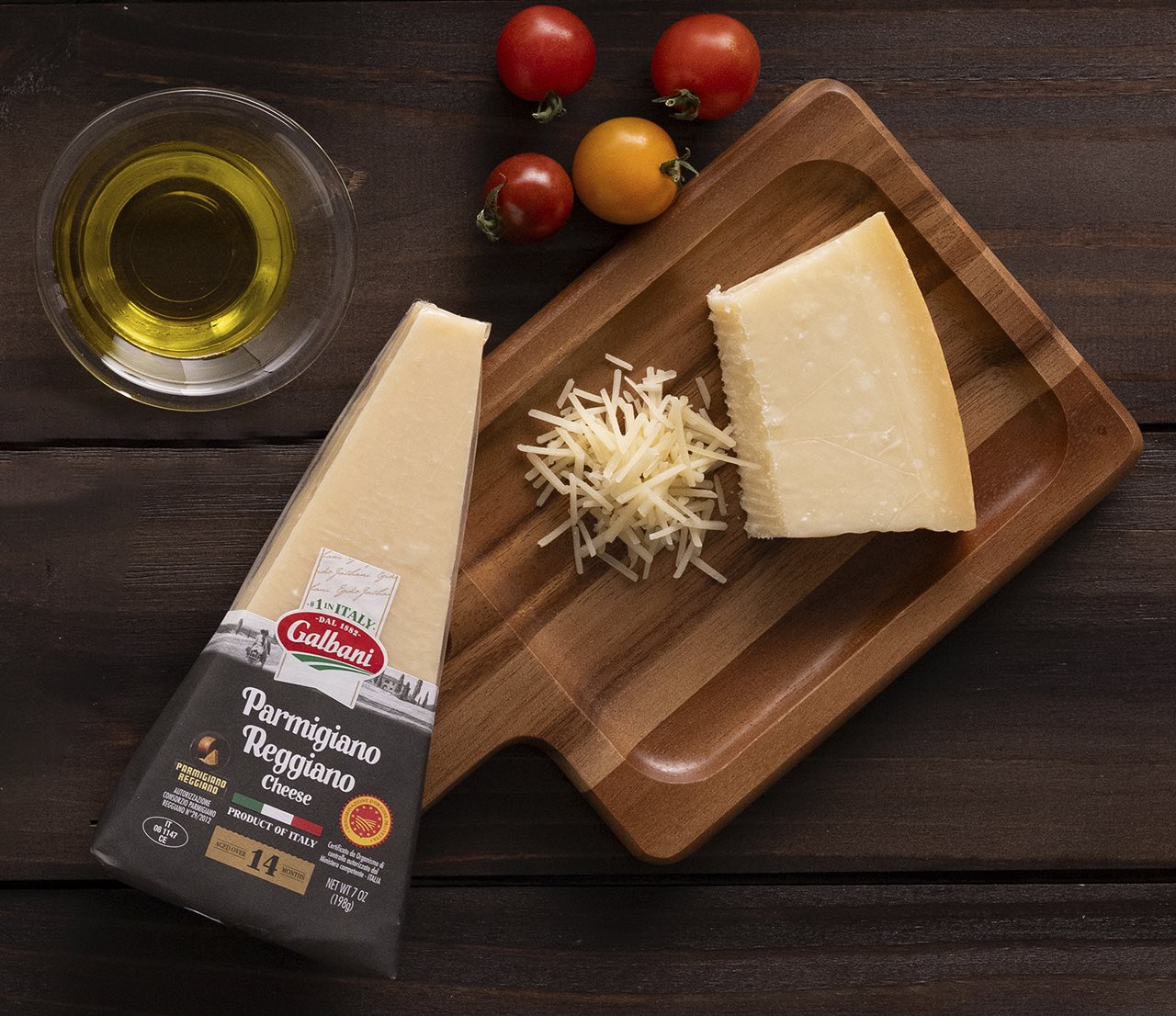 Galbani Parmigiano Reggiano grated cheese in a cutting board next to a small dish of olive oil