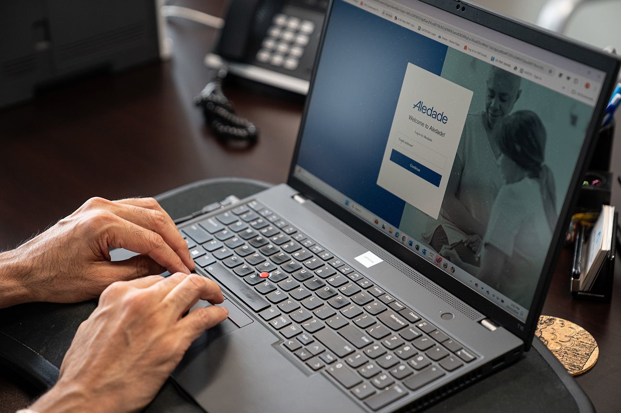 Older woman using laptop to contact Aledade online.