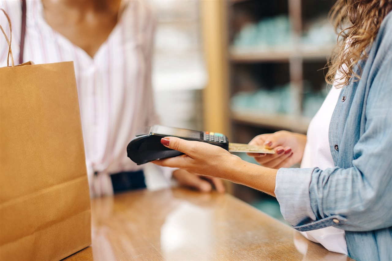 Woman swiping a credit card at a clothing store. Citi's Credit Knowledge Center tells how to maximize card rewards.