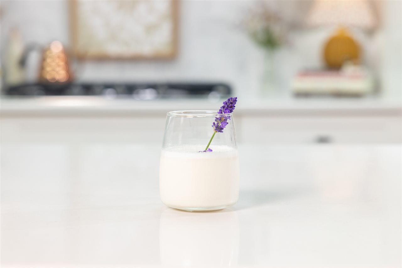 A glass of honey lavender milk, a soothing blend of delicate lavender, golden honey and whole milk, on the counter in the kitchen.