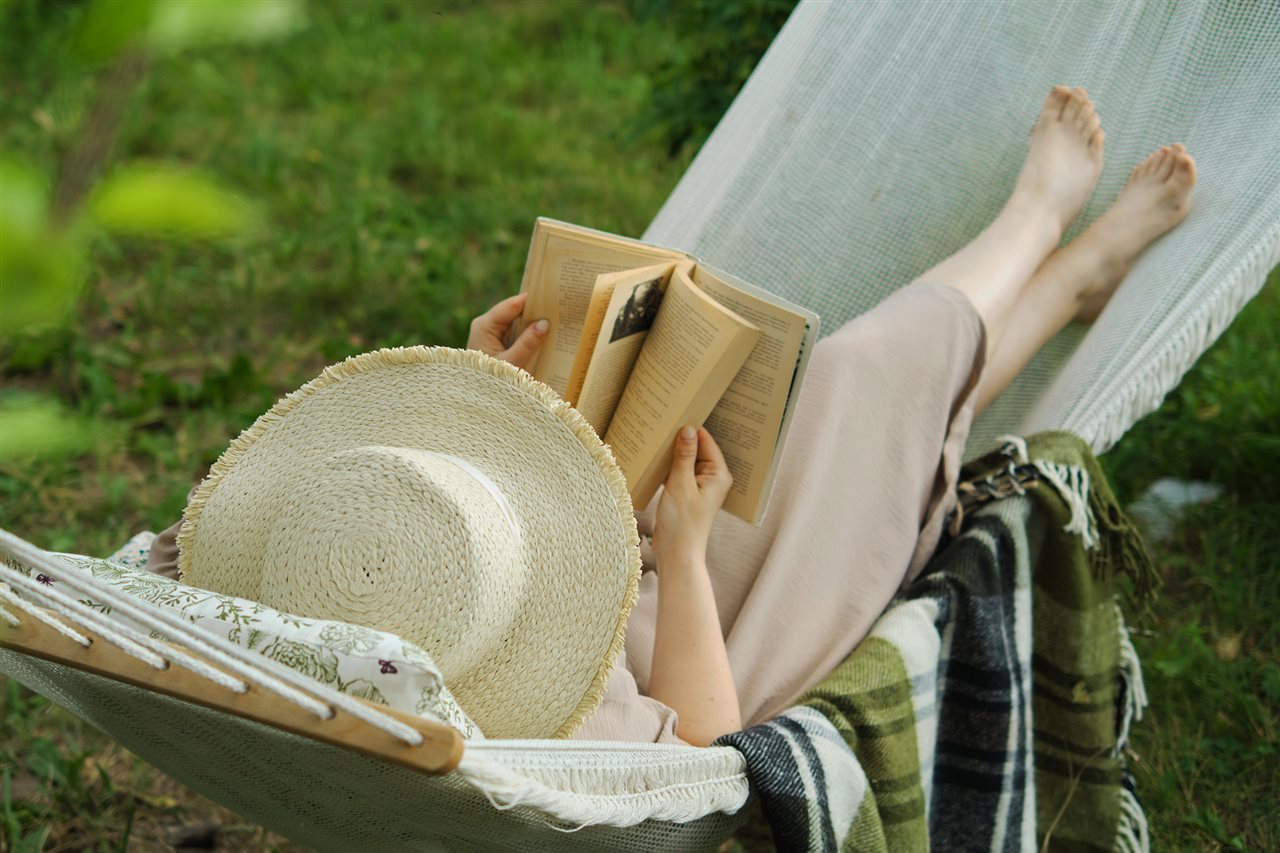 Woman in a hammock reading a book.
