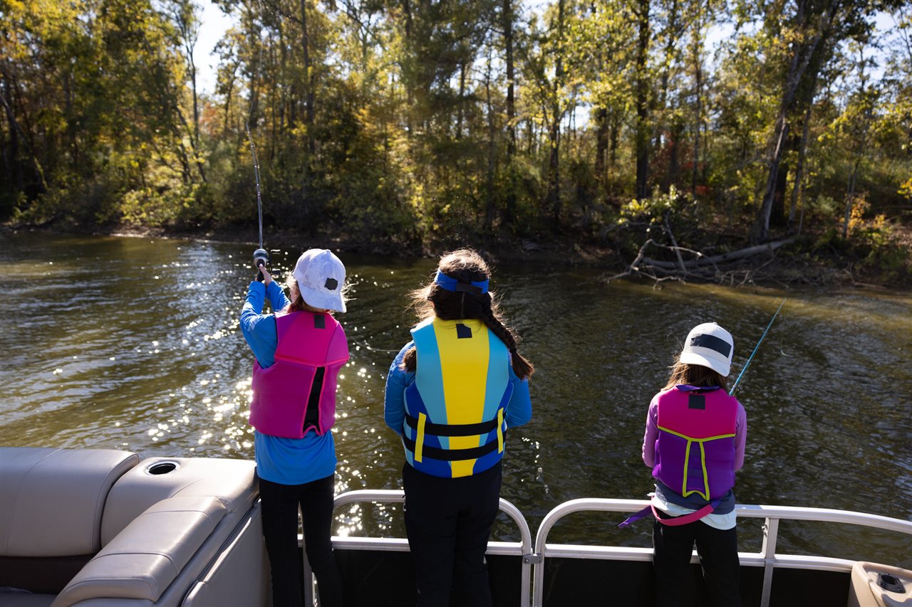 Three pre-teen girls fishing off the back of a boat.  Discover Boating says 