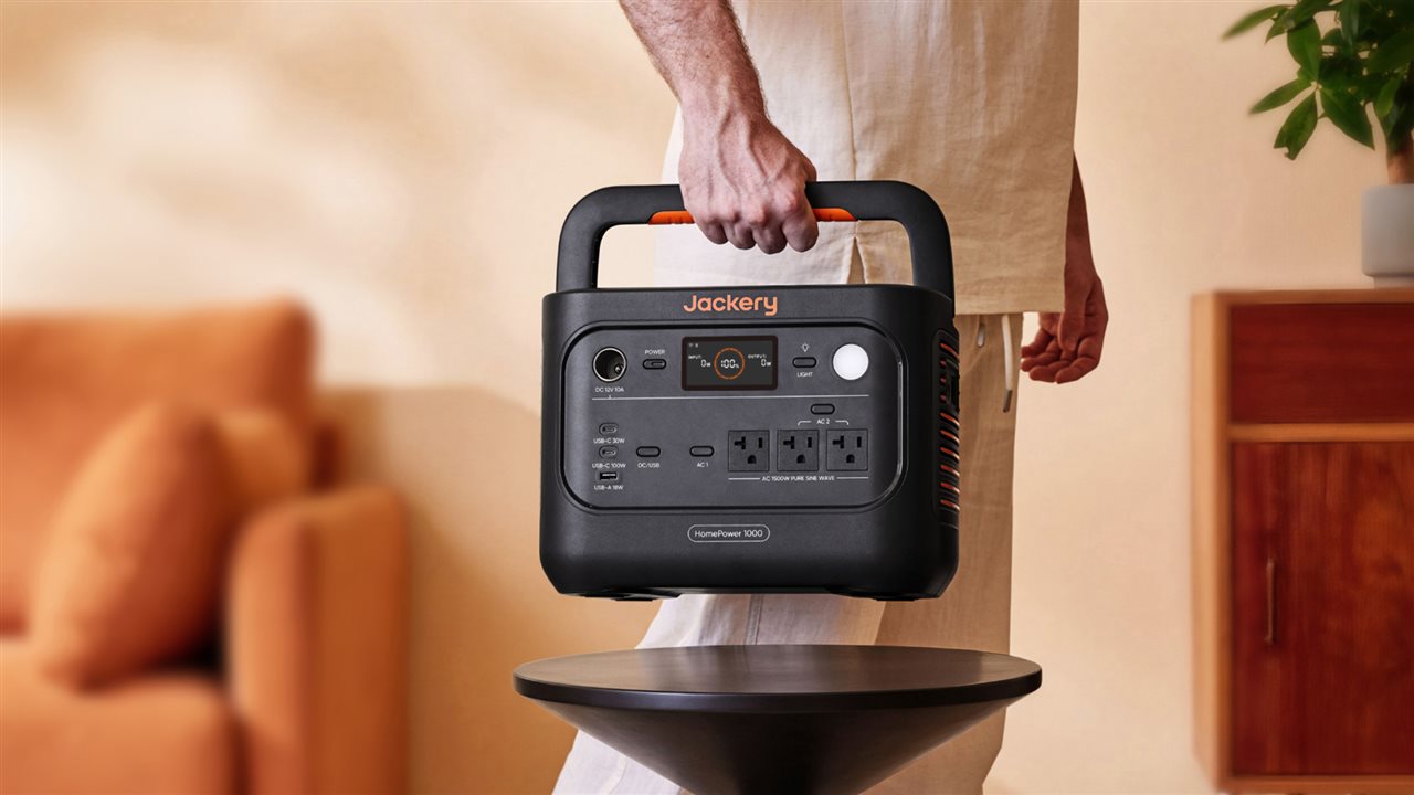 A man lifts his Jackery HomePower 1000 generator from a small table.