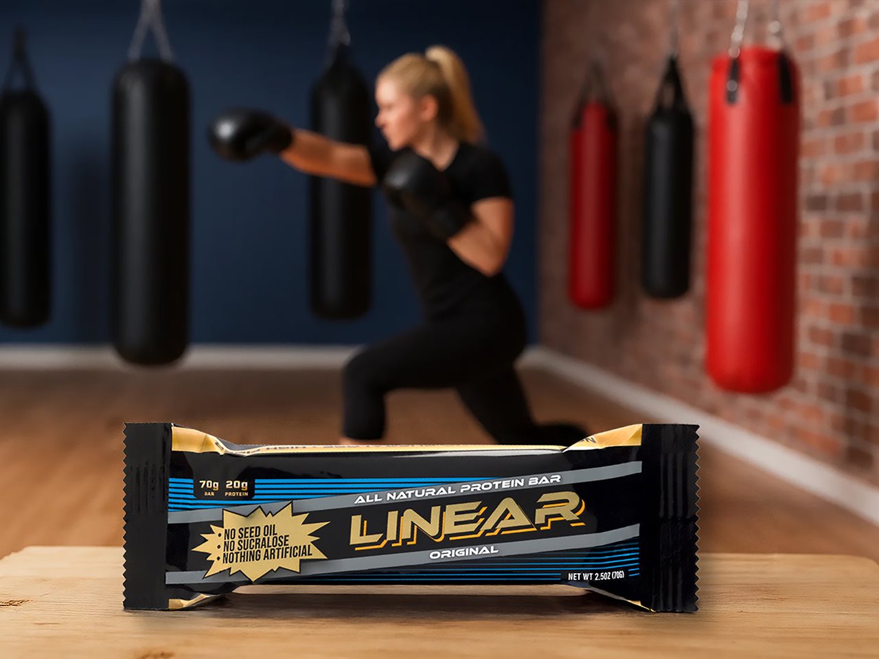 A Linear bar in the foreground with a woman in boxing gloves working out in the background