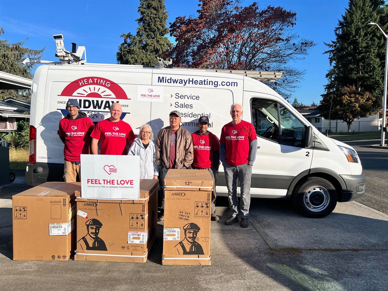 People in red t-shirts in front of a service truck and Lennox Residential HVAC products in delivery boxes.