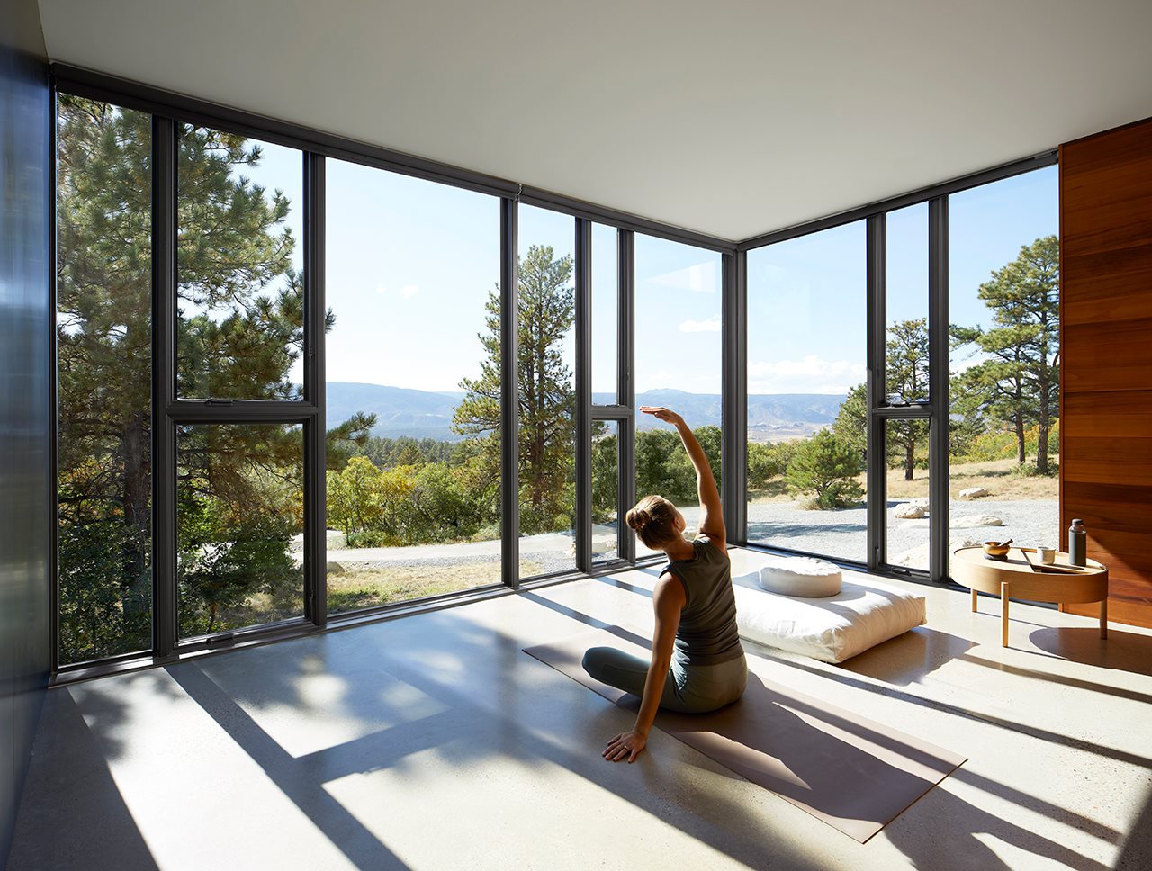 Woman meditating while practicing yoga in a sun room with big beautiful windows.