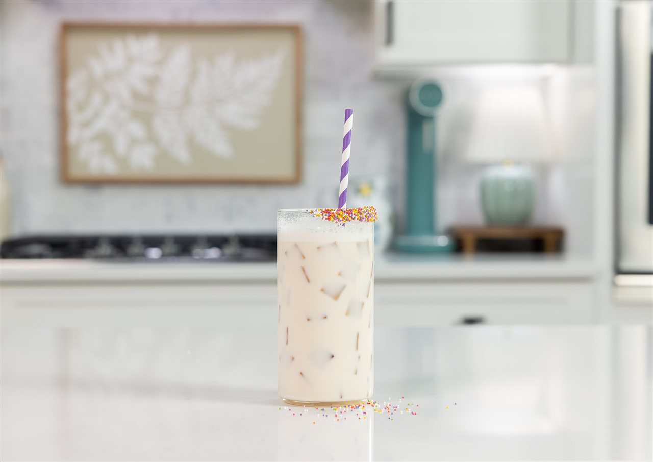 A glass of Organic Valley Birthday Cake Sparkling Milk with confetti dots and a straw.