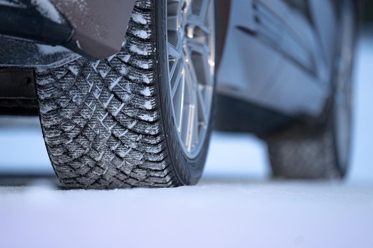 Close up of the tread on the tire on the back passenger side of a car in the snow.
