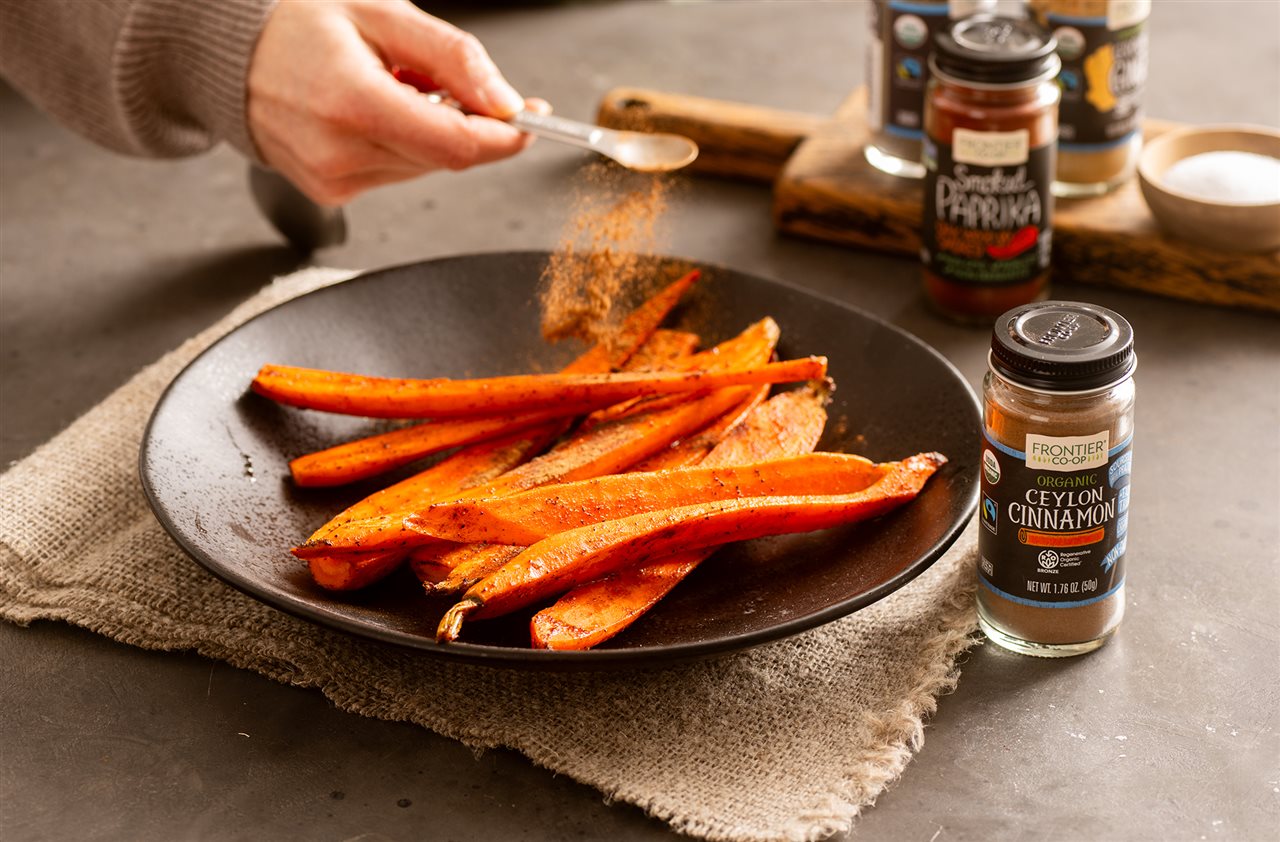 Woman preparing carrotsfor roasting with ceylon cimmamon.