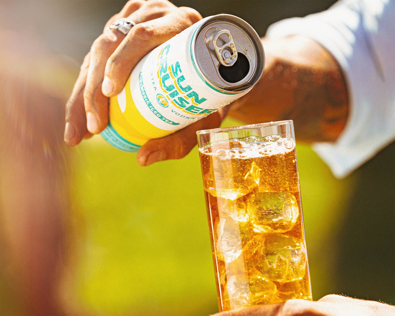 Woman pouring a Sun Cruiser Vodka Ice Tea into a glass of ice