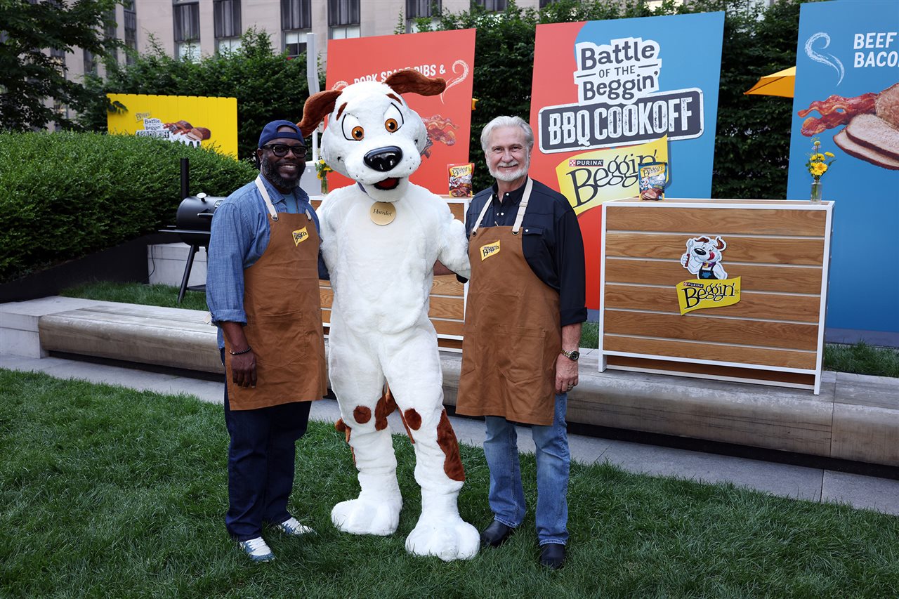Two men and a dog mascot outside