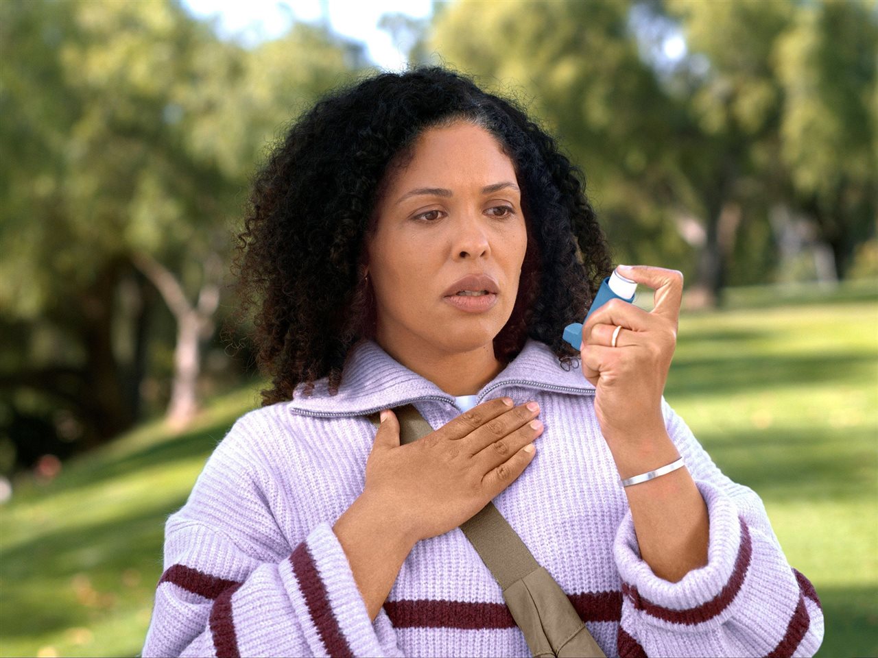 Woman in park with inhaler. Ask your doctor about a different type of asthma control. Learn more at asthma.com.