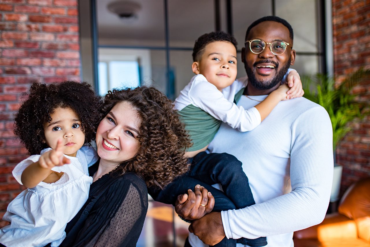 Smiling family of four outside their suburban home. UnidosUS is the nation's largest Hispanic civil rights and advocacy organization.