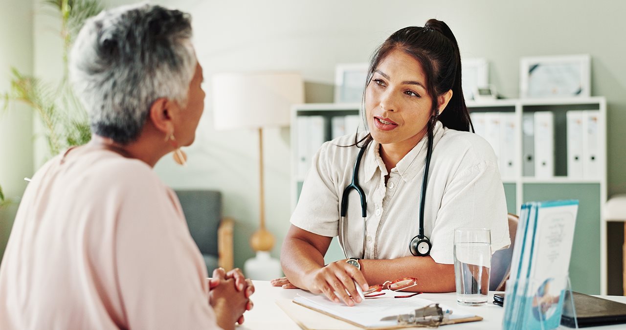 Older woman talking with her doctor across the desk from her