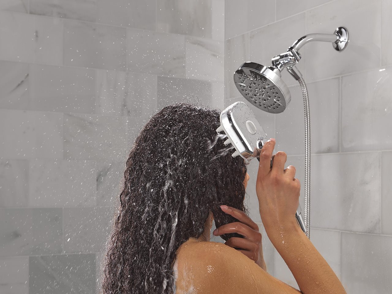 A woman uses the VersaCurl Tool on her dark curly hair in the shower.