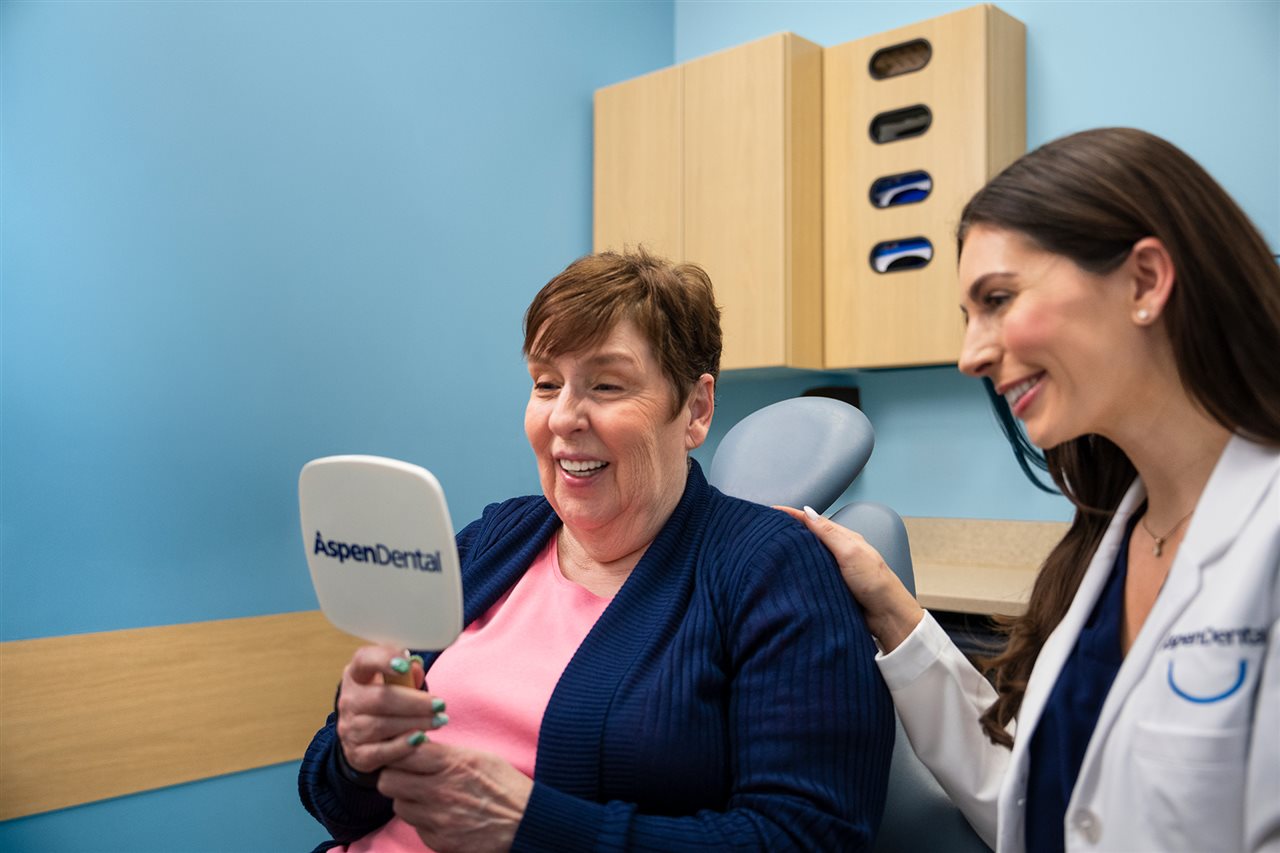 Dr White and a patient looking in the mirror at her new tooth implants