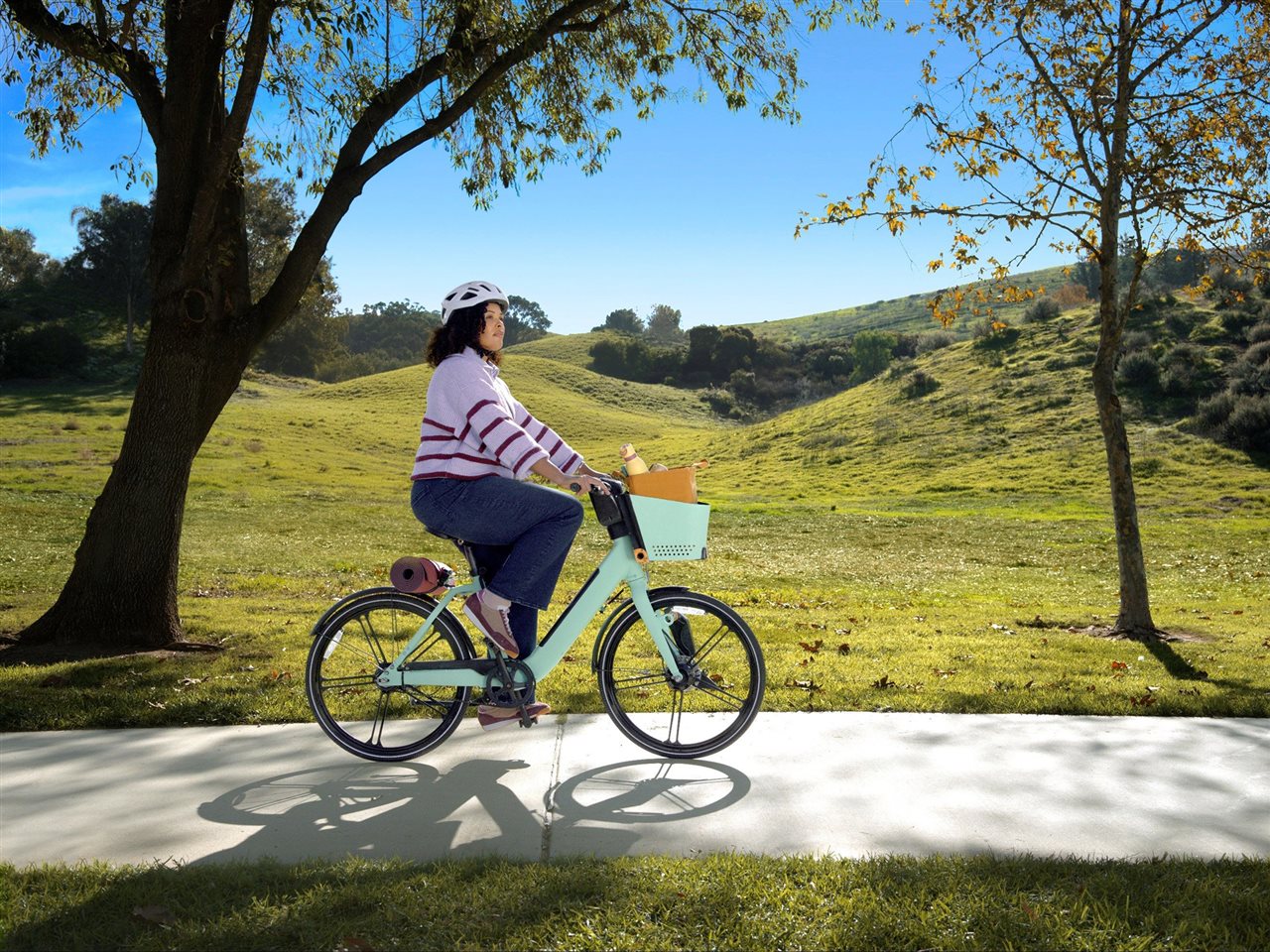 Woman wearing a helmet on a bike ride in the park. Learn more about asthma asthma.com.