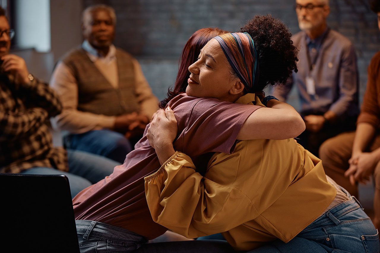 Two women huging during support group converstion.