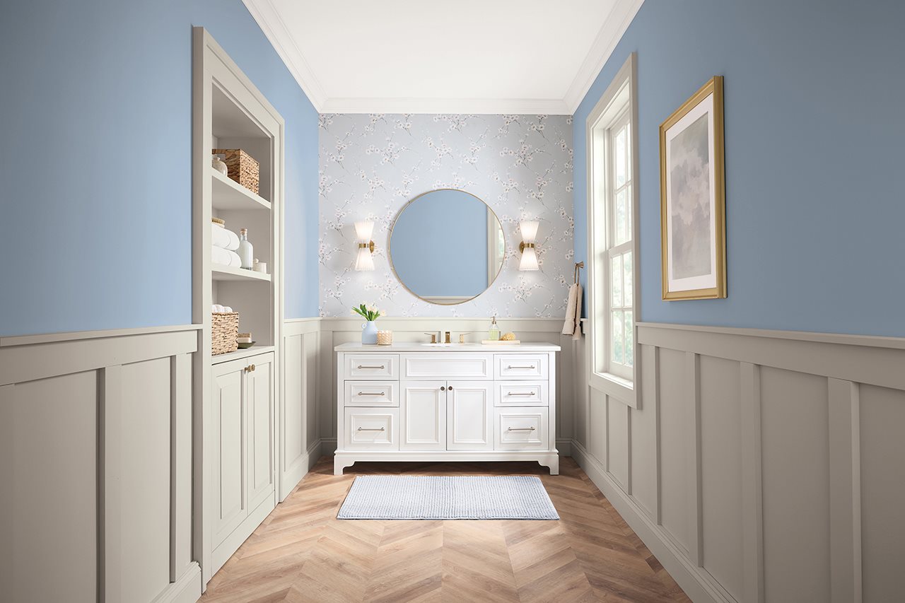 Bathroom with powder blue walls and white cabinetry and wainscotting.