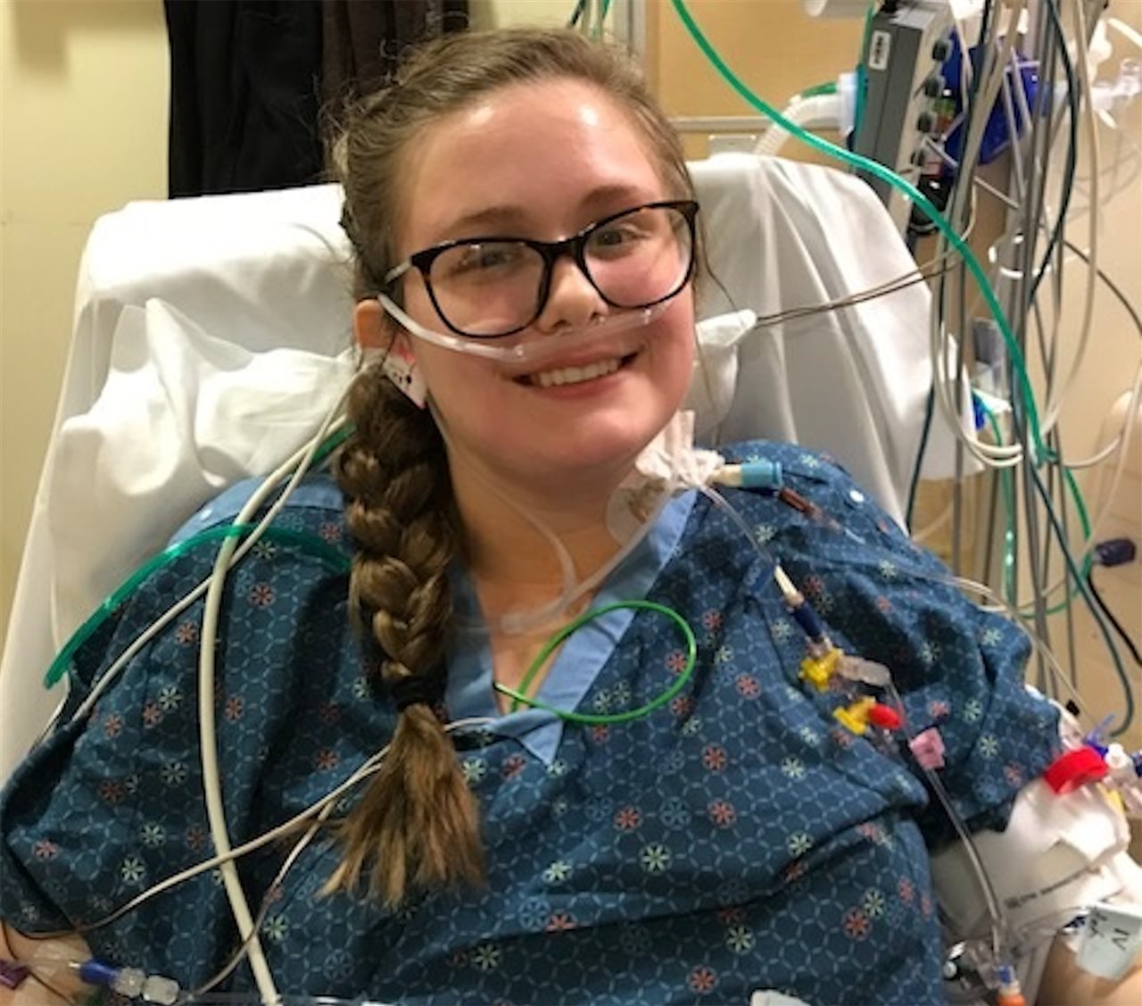 Sarah Johnson Lowery in a hospital bed, hooked up to monitors, smiling.