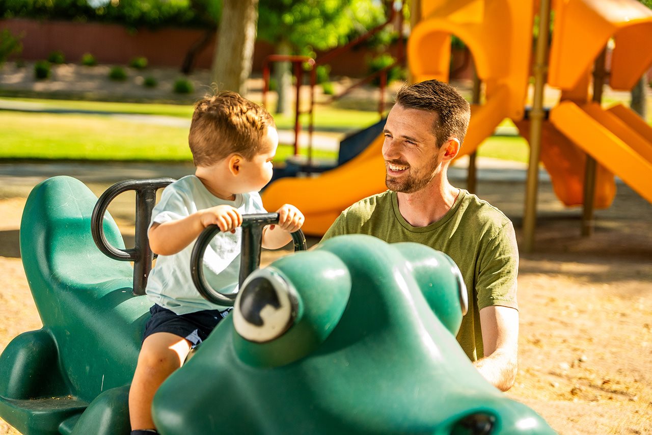 John playing with his son on the playground