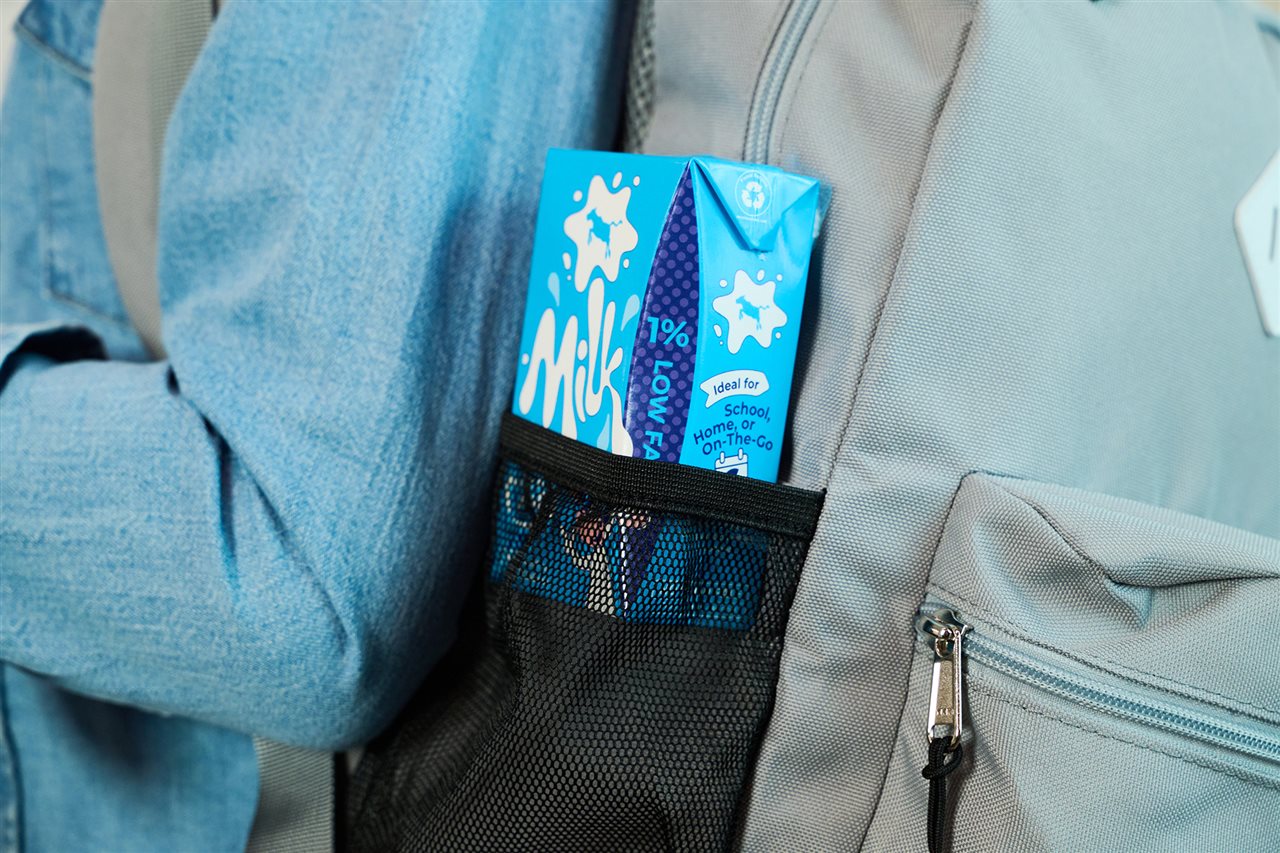 Child with a TetraPak carton of milk in their backpack.