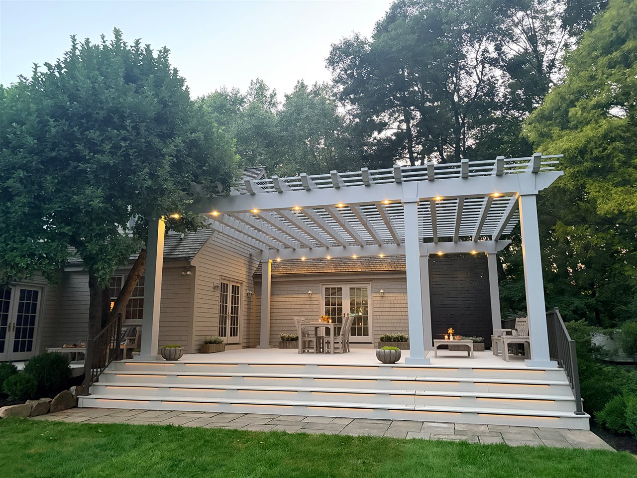 A white backyard patio lit up in the evening.